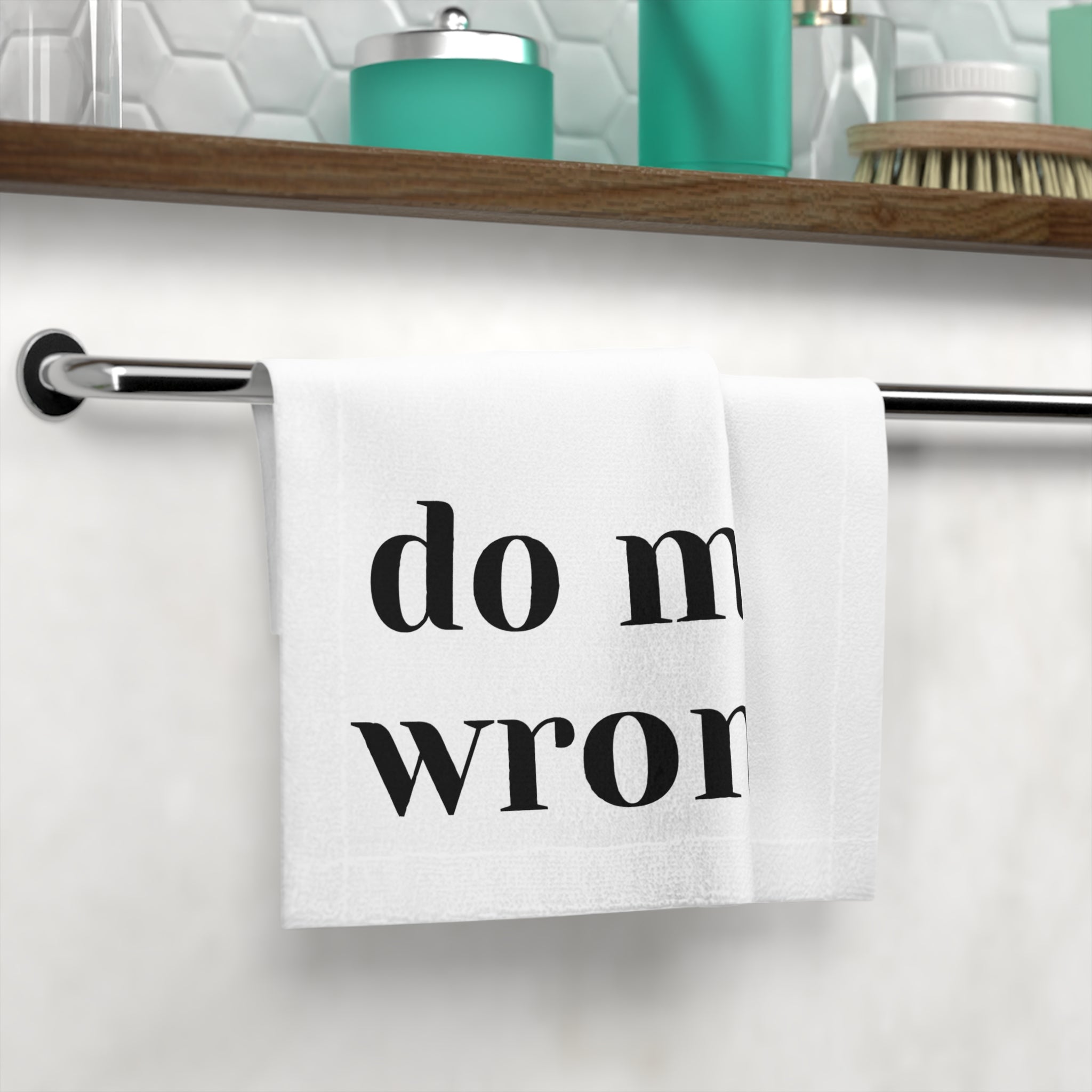 White hand towel with 'do me wrong.' text displayed on a bathroom towel rack, adding a playful and sexy touch to the decor.