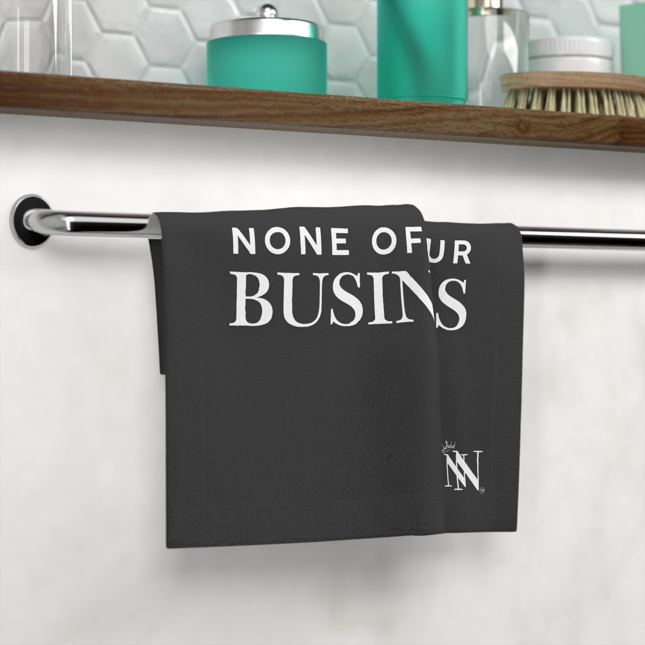 Black 'None of Your Business' hand towel displayed on a bathroom towel rack, surrounded by modern bathroom decor, ideal for playful and sexy cleanup.